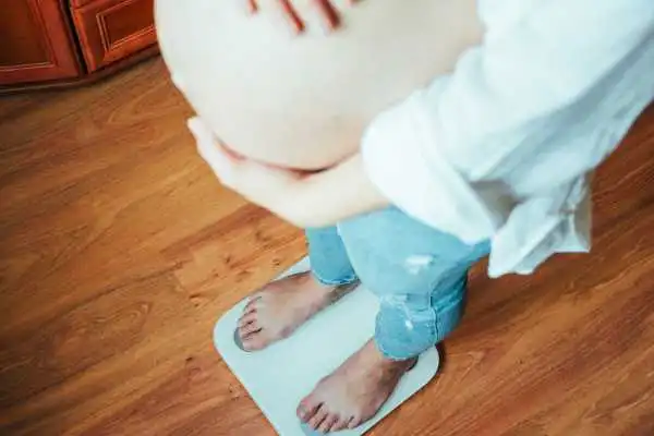 Image of woman weighing herself and experiencing weight gain through pregnancy Hayes